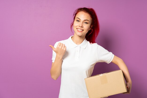 Livreur adolescent isolé sur fond violet avec le pouce en l'air geste et souriant