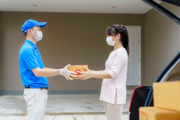 Livreur asiatique portant un masque facial tenant une boîtes en carton