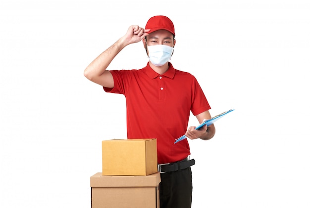 Livreur asiatique portant un masque facial en uniforme rouge debout avec boîte aux lettres isolé sur fond blanc. service de livraison express pendant covid19.