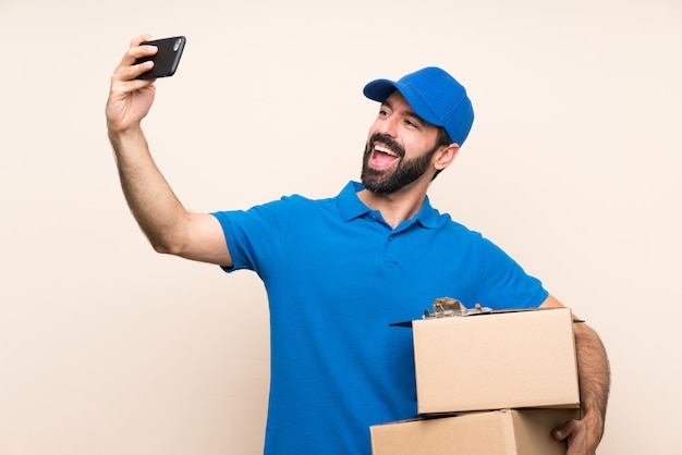 Livreur avec barbe sur mur isolé faisant un selfie