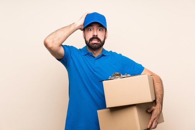 Livreur avec barbe sur un mur isolé frustré et prend les mains sur la tête