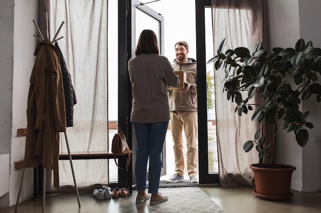 Un livreur avec une boîte à colis et un client à la maison.