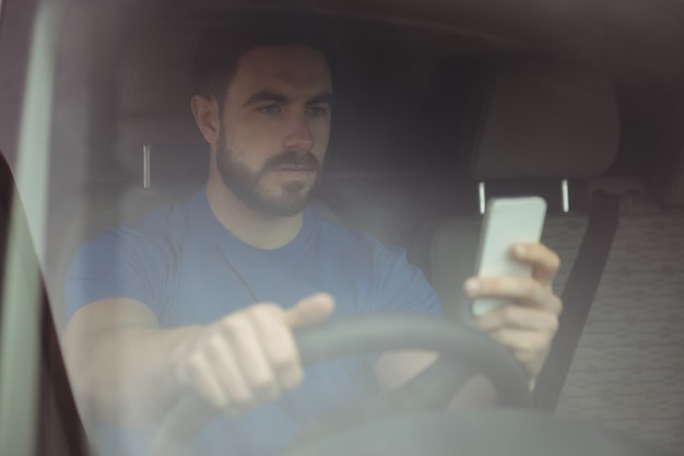 Livreur conduisant sa camionnette en utilisant un smartphone