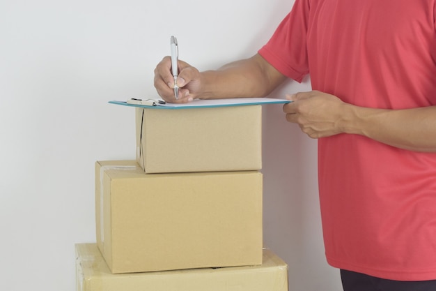 Photo livreur écrit sur un presse-papiers avec des boîtes aux lettres de colis sur fond blanc concept de livraison