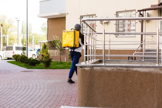 le livreur envoie un sac de nourriture au bouton de la porte pour un contact sans contact ou sans contact avec le livreur devant la maison pour une distanciation sociale en cas de risque d'infection.