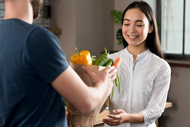 Photo livreur livrant l'épicerie à une femme à la maison