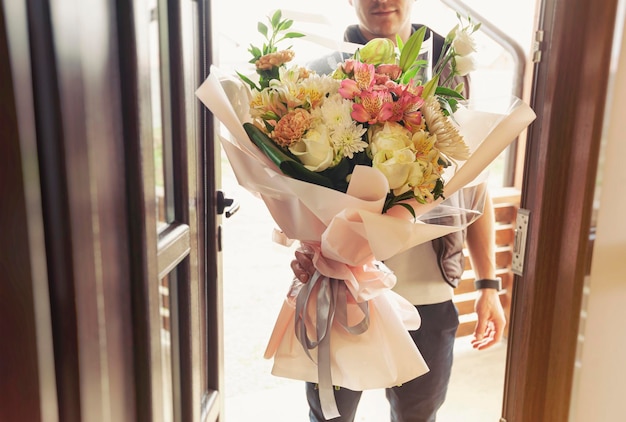 Le livreur livre un bouquet de belles fleurs à la maison