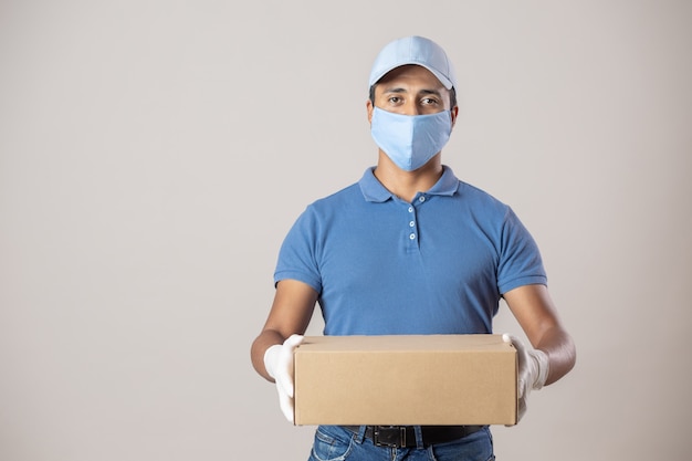 Livreur mexicain en uniforme se protégeant avec un masque et des gants fonctionnant en raison du verrouillage