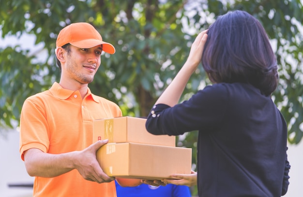 Livreur en orange remet des colis à une femme