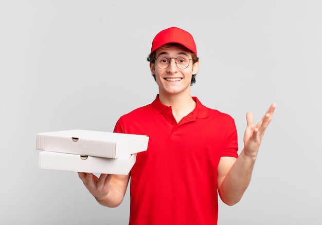 Livreur de pizza garçon se sentant heureux, surpris et joyeux, souriant avec une attitude positive, réalisant une solution ou une idée