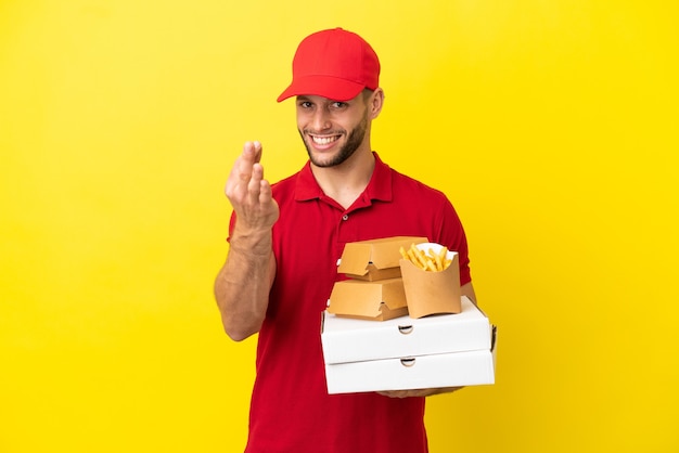 Livreur de pizza ramasser des boîtes de pizza et des hamburgers sur fond isolé faisant un geste d'argent