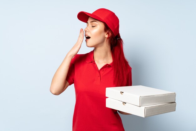 Livreur de pizza tenant une pizza sur fond isolé bâillement et couvrant la bouche grande ouverte avec la main
