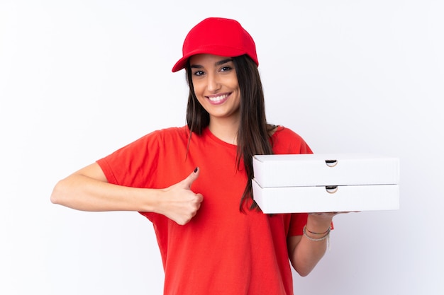 Livreur de pizza tenant une pizza sur un mur blanc avec les pouces vers le haut parce que quelque chose de bien s'est produit