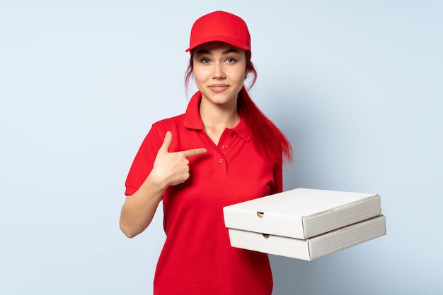 Livreur de pizza tenant une pizza sur un mur isolé avec une expression faciale surprise