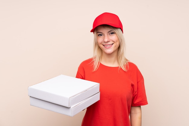 Livreur de pizza tenant une pizza sur un mur isolé, souriant beaucoup