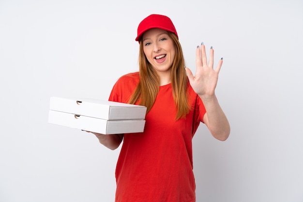 Livreur de pizza tenant une pizza sur le mur rose saluant avec la main avec une expression heureuse