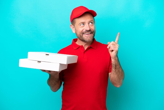 Livreur de pizza avec uniforme de travail ramassant des boîtes de pizza isolées sur fond bleu pointant vers une excellente idée