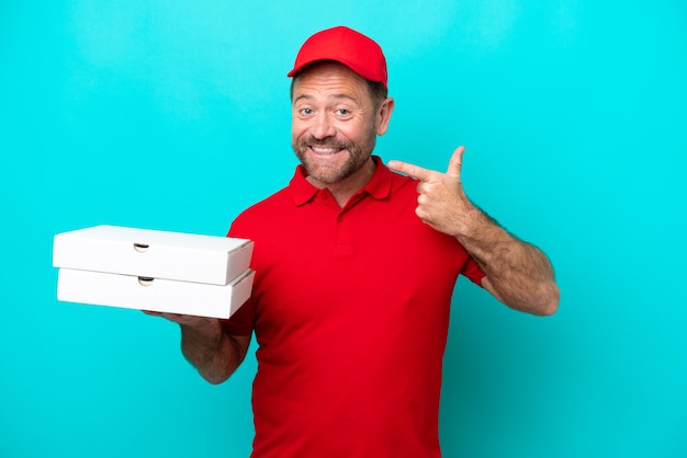 Livreur de pizza avec uniforme de travail ramasser des boîtes de pizza isolées sur fond bleu donnant un geste du pouce levé