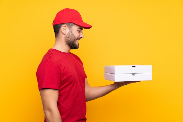 Livreur de pizza avec uniforme de travail ramasser des boîtes à pizza sur jaune isolé avec une expression heureuse