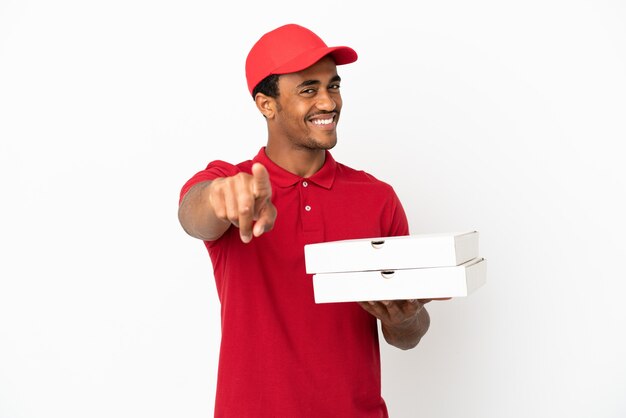 Livreur de pizzas afro-américaines ramassant des boîtes de pizza sur un mur blanc isolé pointant vers l'avant avec une expression heureuse