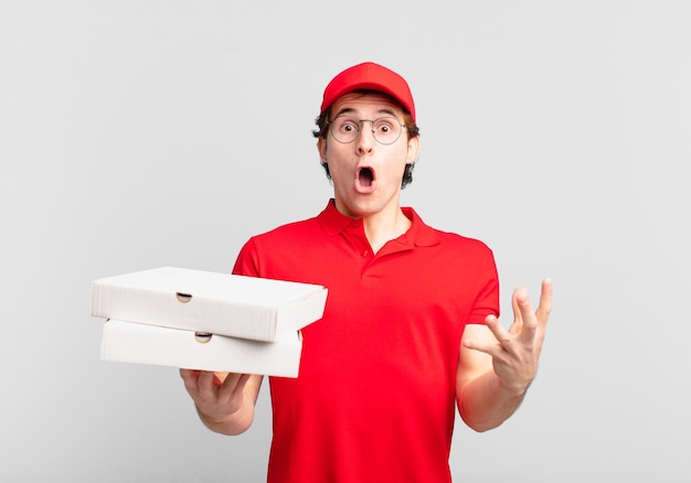 Livreur de pizzas se sentant extrêmement choqué et surpris, anxieux et paniqué, avec un regard stressé et horrifié