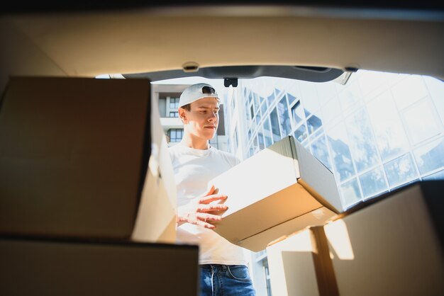 Livreur ramassant la boîte de la voiture.