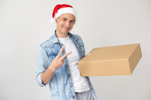 Livreur riant en chapeau de père noël au téléphone, debout et tenant une boîte en carton d'une main. isolé sur blanc.