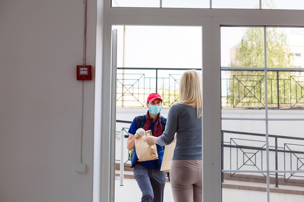 livreur avec sac à dos thermo et femme souriante au bureau