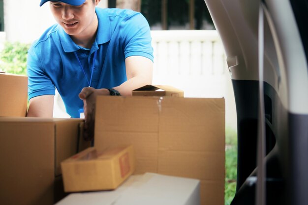 Un livreur sort des colis de la voiture.