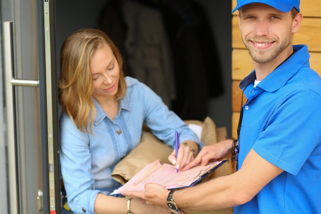 Livreur souriant en uniforme bleu livrant une boîte à colis au concept de service de messagerie destinataire Livreur souriant en uniforme bleu