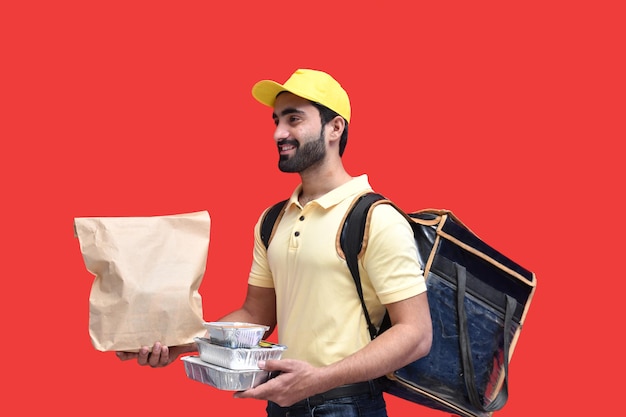 livreur en t-shirt jaune transportant un sac en papier sac à dos avec des plats à emporter modèle pakistanais indien