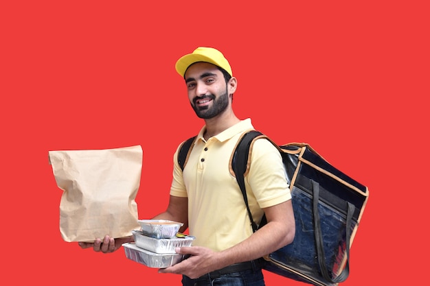 livreur en t-shirt jaune transportant un sac en papier sac à dos avec des plats à emporter paki indien