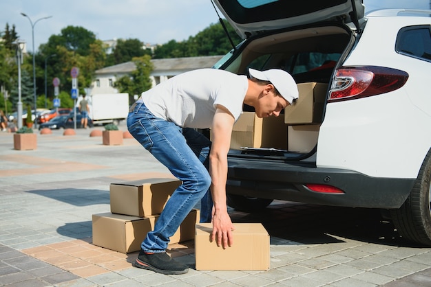 Le livreur tient des colis à la voiture, livrant