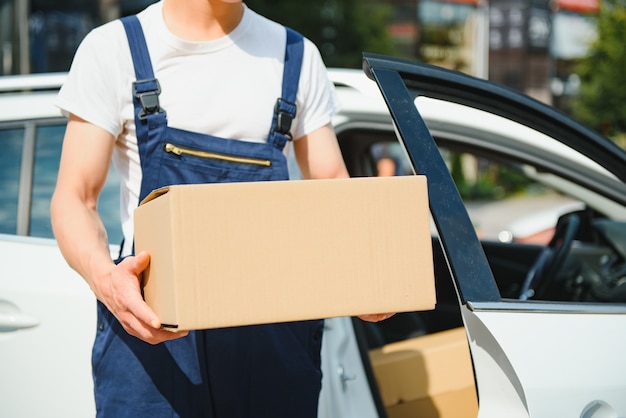 Le livreur tient des colis à la voiture, livrant