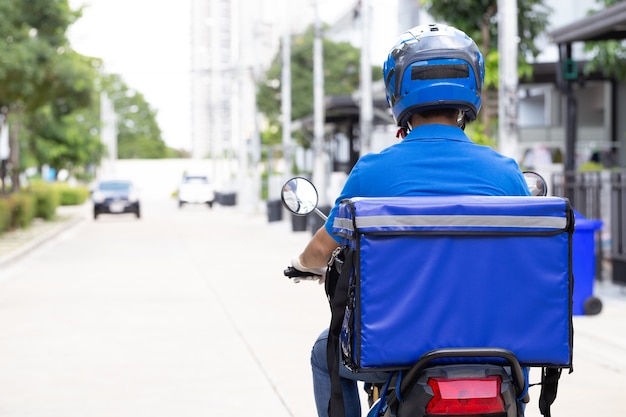 Livreur en uniforme bleu équitation moto et boîte de livraison