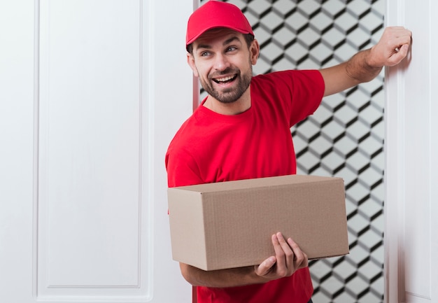 Livreur vue de face portant l'uniforme rouge et frappant à la porte