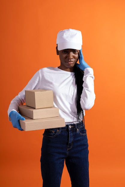 Photo une livreuse afro-américaine confiante dans une casquette blanche et des gants en caoutchouc bleus