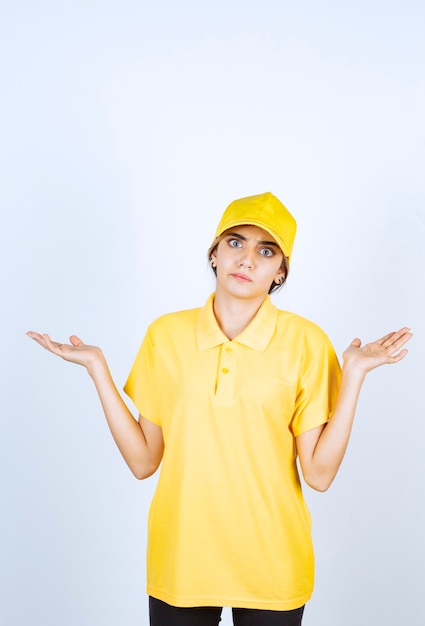 Livreuse en uniforme jaune debout et haussant les bras.