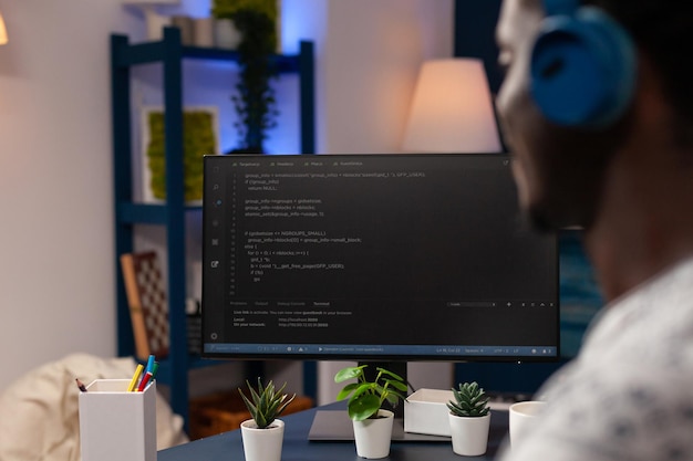 Logiciel de programmation de jeunes développeurs afro-américains pour le site Web tapant le code html développant une application. Homme d'affaires portant des écouteurs travaillant à l'infographie javascript. Travail à distance depuis la maison