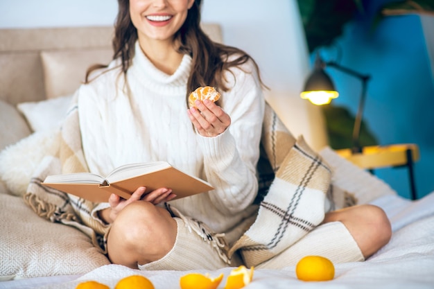 Loisir. Belle jeune femme lisant un livre dans sa chambre