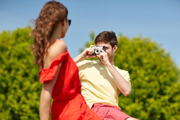 Photo loisir, photographie, vacances d'été et concept de personnes - couple heureux avec caméra photographiant à l'extérieur