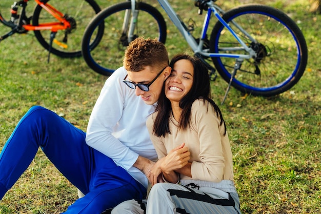 Loisirs d'un jeune couple élégant sur la pelouse sur un fond de vélo