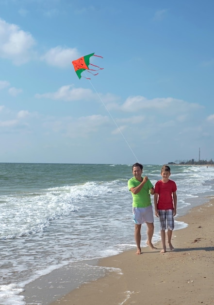 Loisirs Repos des parents avec enfants Papa et fils font voler un cerf-volant près de la mer