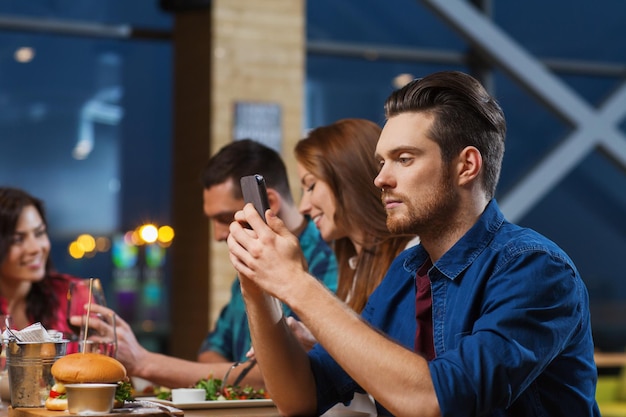 loisirs, technologie, dépendance à Internet, mode de vie et concept de personnes - homme avec smartphone et amis au restaurant