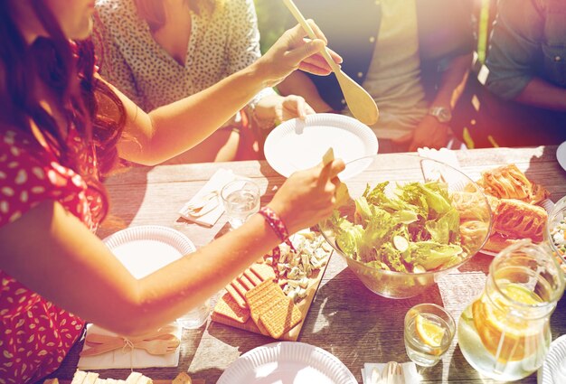 Photo loisirs, vacances, manger, personnes et concept alimentaire - amis heureux en train de dîner à la fête d'été