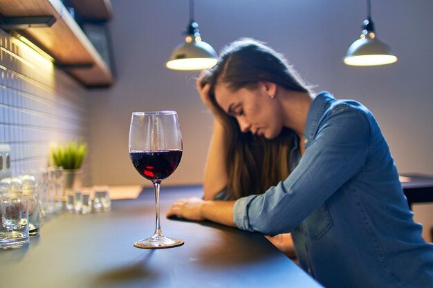 Lonely bouleversé déprimé malheureux femme buvant souffrant d'abus de dépendance à l'alcool avec un verre de vin rouge seul à la maison