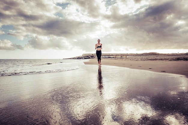 Lonely runner lady young caucasian girl à la plage en style pieds nus s'exécutant sur le rivage