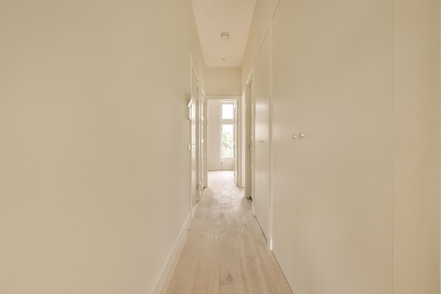 un long couloir blanc avec des murs blancs et des planchers en bois
