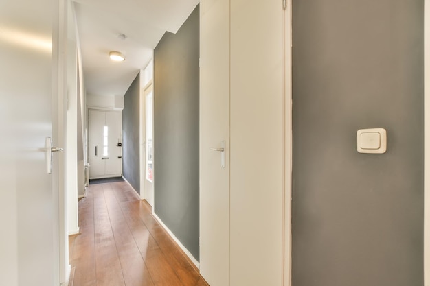 Un long couloir droit dans les tons gris avec parquet dans une maison moderne