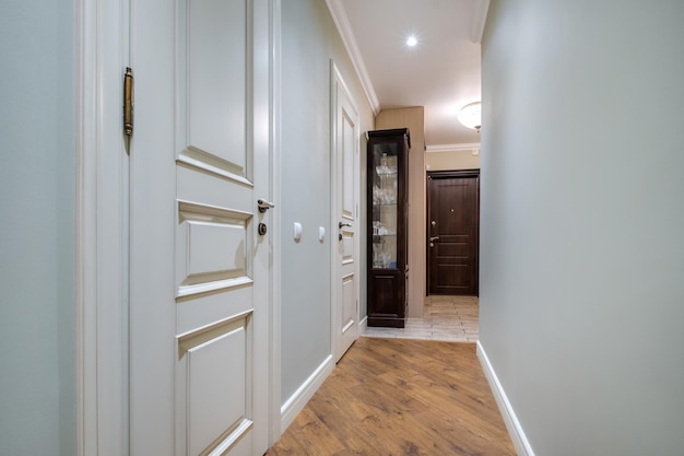 Long couloir à l'intérieur du hall d'entrée d'appartements modernes avec portes, armoires, étagères et miroir